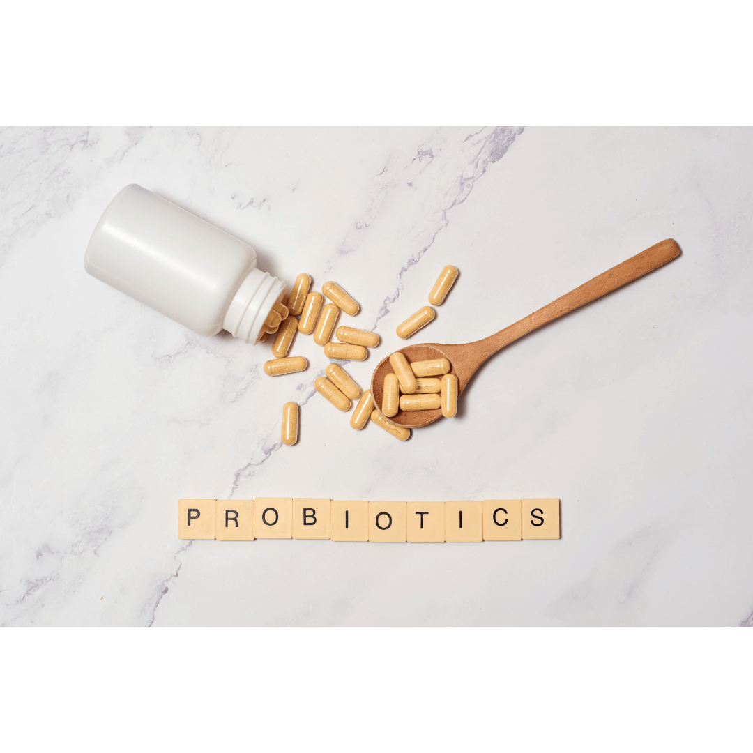 Cápsulas de probióticos en frasco blanco y cuchara de madera sobre fondo claro con la palabra probiotics