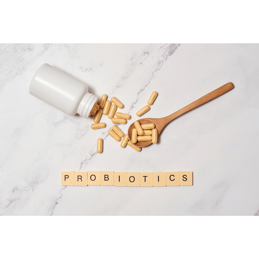 Cápsulas de probióticos en frasco blanco y cuchara de madera sobre fondo claro con la palabra probiotics