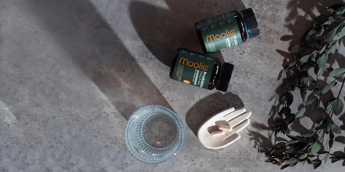 Dos tarros de Moolic con 2 capsulas y 1 vaso de agua