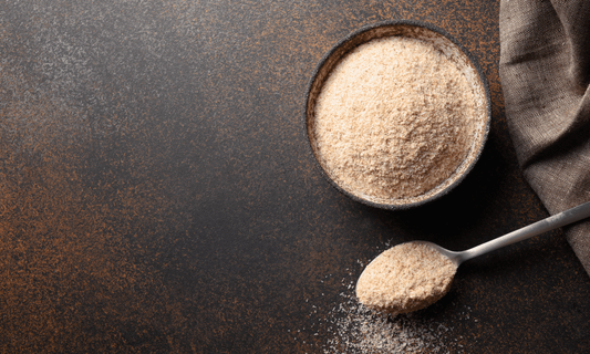 Polvo de psyllium en bowl oscuro con cuchara dosificadora, fuente de fibra soluble para mejorar la digestión y regular el tránsito intestinal